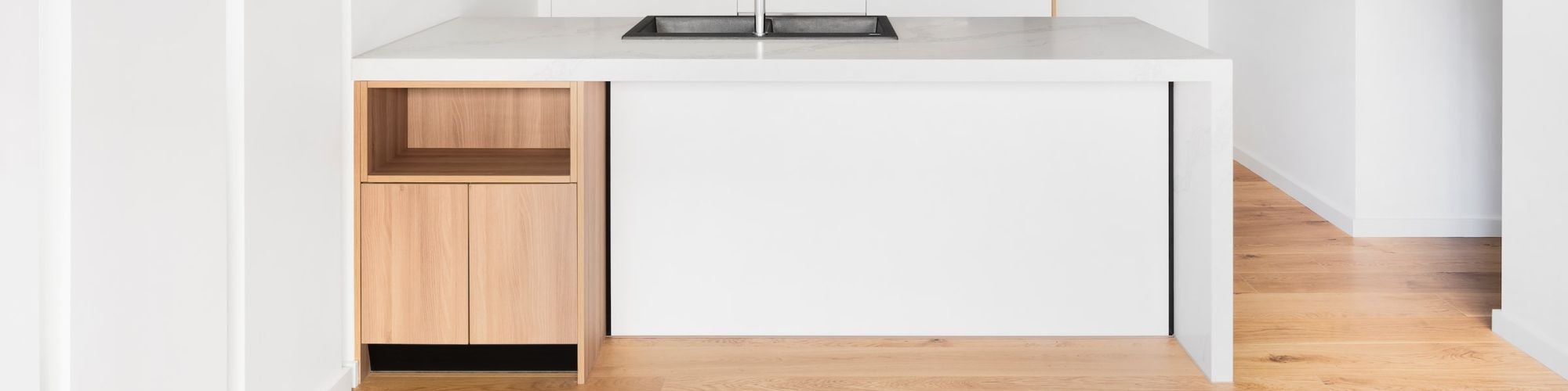 Wood flooring in a bright and modern kitchen with white cabinets.